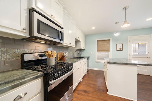 kitchen with a kitchen island, appliances with stainless steel finishes, decorative light fixtures, white cabinetry, and sink