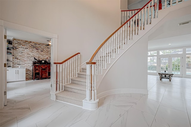 stairway featuring french doors and a towering ceiling