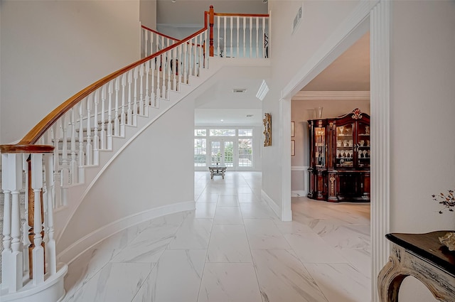 entryway featuring crown molding and a towering ceiling