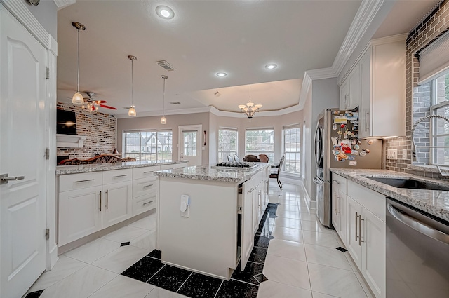 kitchen featuring decorative light fixtures, a center island, white cabinets, and appliances with stainless steel finishes