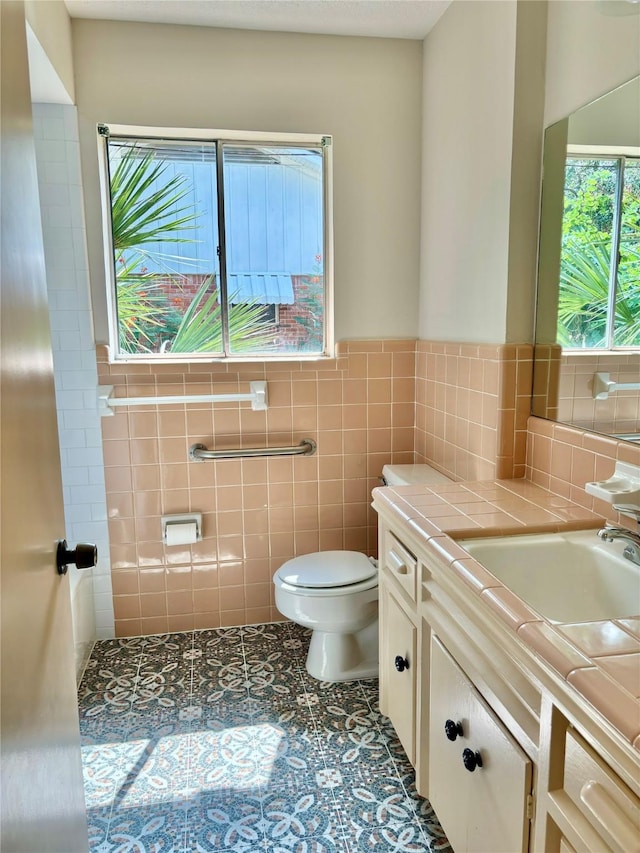 bathroom with tile patterned floors, vanity, toilet, and tile walls