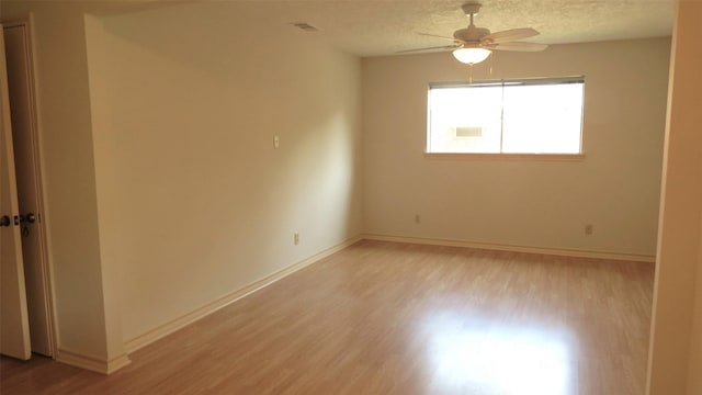 unfurnished room with ceiling fan, a textured ceiling, and light wood-type flooring