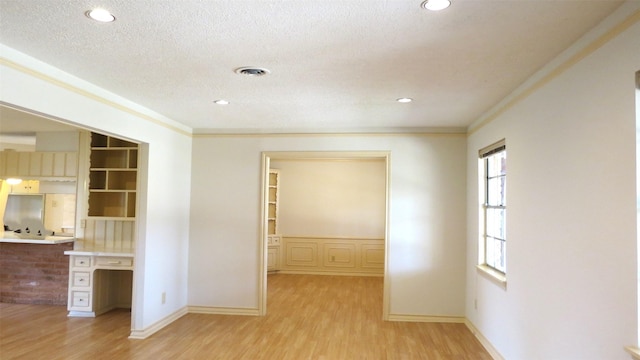 hall featuring ornamental molding, a textured ceiling, and light wood-type flooring