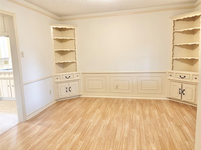 unfurnished room with ornamental molding, a textured ceiling, and light wood-type flooring