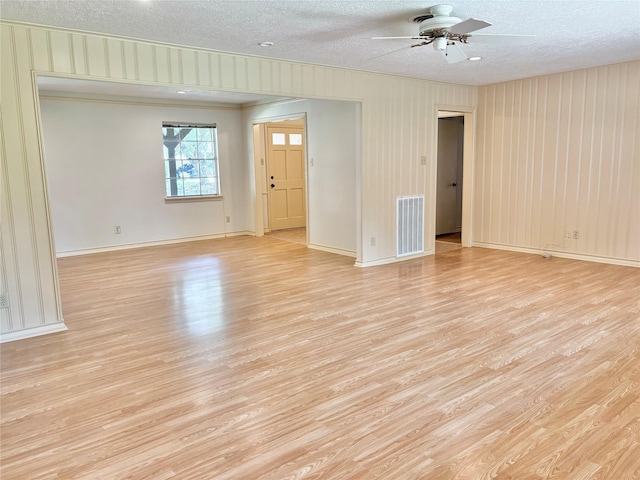 empty room featuring a textured ceiling, light hardwood / wood-style flooring, and ceiling fan