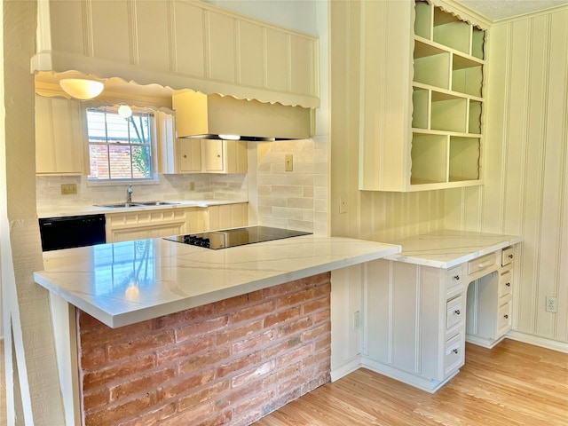 kitchen with kitchen peninsula, sink, black appliances, light stone countertops, and light hardwood / wood-style flooring