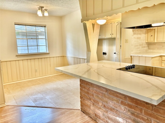 kitchen with light hardwood / wood-style flooring, light stone countertops, kitchen peninsula, and a textured ceiling