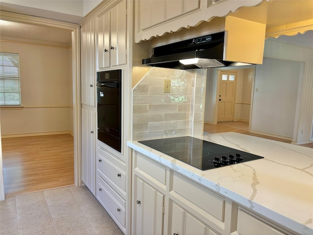 kitchen with light tile patterned flooring, backsplash, light stone counters, black appliances, and crown molding