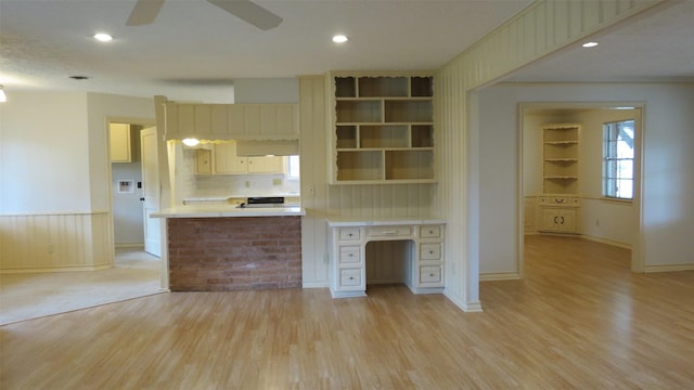 kitchen featuring built in shelves, built in desk, ceiling fan, and light wood-type flooring