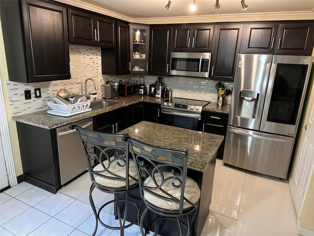 kitchen featuring tasteful backsplash, dark brown cabinets, light tile patterned floors, appliances with stainless steel finishes, and dark stone counters