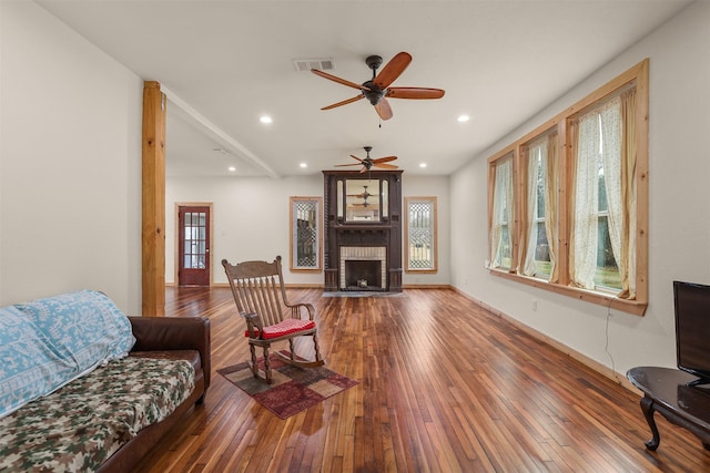 living room with a brick fireplace, dark hardwood / wood-style floors, and ceiling fan