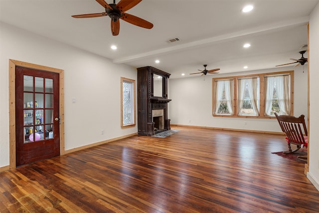 unfurnished living room featuring beam ceiling, ceiling fan, dark wood-type flooring, and a fireplace