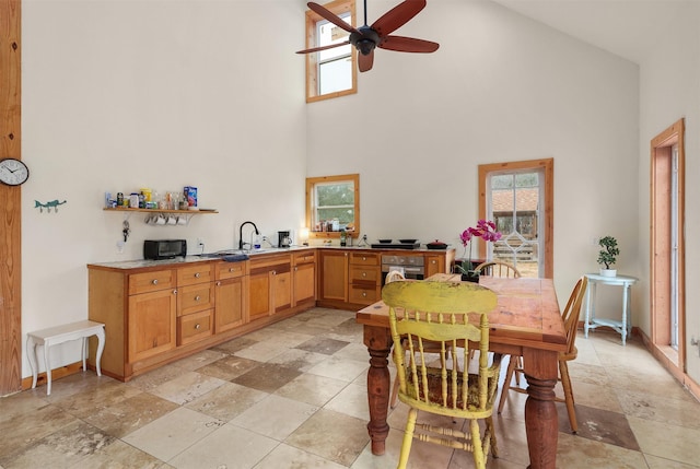 dining room with ceiling fan, a healthy amount of sunlight, sink, and a towering ceiling