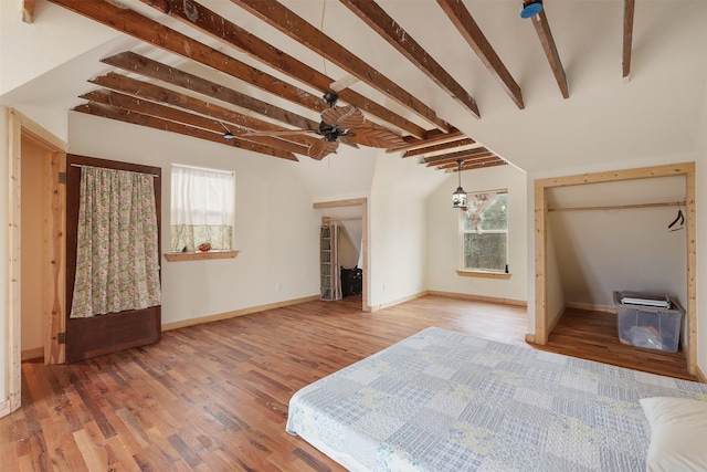 unfurnished bedroom with wood-type flooring, lofted ceiling with beams, and multiple windows