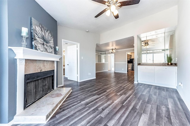 unfurnished living room with a tile fireplace, dark hardwood / wood-style floors, and ceiling fan