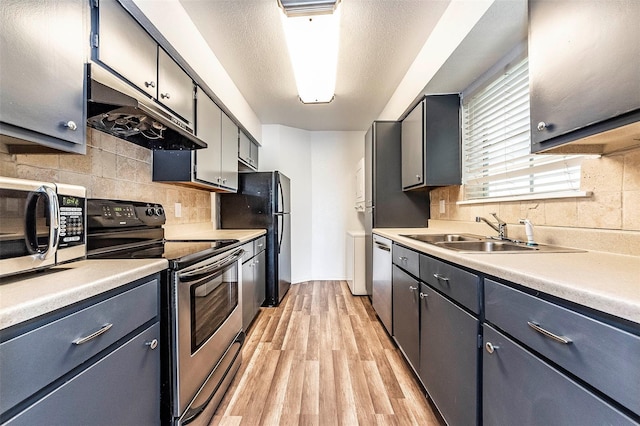kitchen featuring backsplash, appliances with stainless steel finishes, sink, and light wood-type flooring