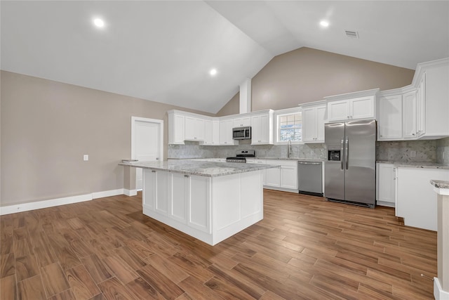 kitchen with stainless steel appliances, a center island, wood-type flooring, and white cabinets