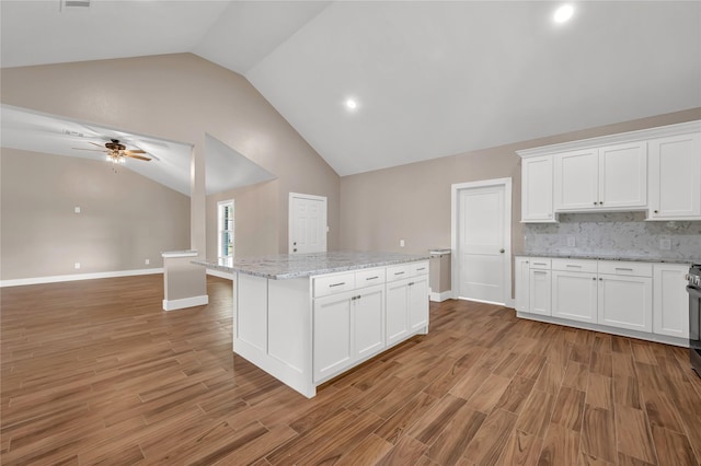 kitchen with white cabinetry, light wood-type flooring, light stone countertops, and a kitchen island