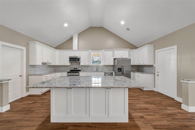 kitchen featuring stainless steel appliances, light stone countertops, a kitchen island, and white cabinets