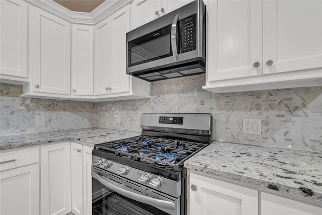 kitchen featuring stainless steel appliances, backsplash, white cabinets, and light stone counters