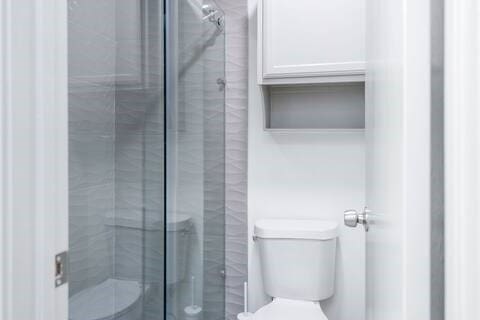 bathroom with a shower with shower door and toilet