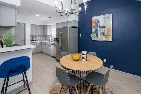 dining room featuring sink, a chandelier, and light hardwood / wood-style flooring