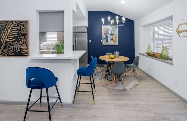 dining room featuring an inviting chandelier, lofted ceiling, light hardwood / wood-style floors, and sink