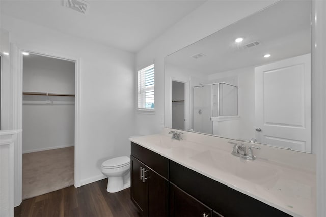 bathroom with wood-type flooring, toilet, a shower with door, and vanity