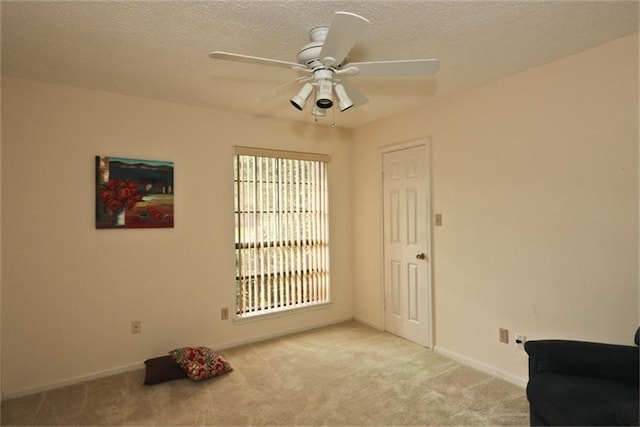 living area featuring ceiling fan, light carpet, and a textured ceiling