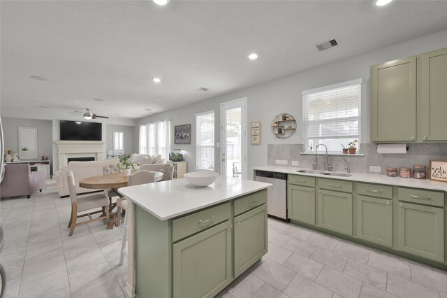 kitchen featuring sink, tasteful backsplash, green cabinetry, a center island, and stainless steel dishwasher