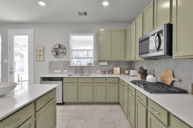 kitchen with tasteful backsplash, green cabinets, stainless steel appliances, and sink