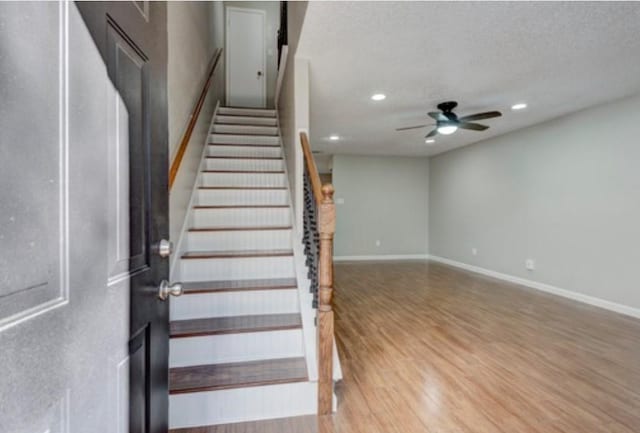 staircase featuring wood-type flooring, a textured ceiling, and ceiling fan