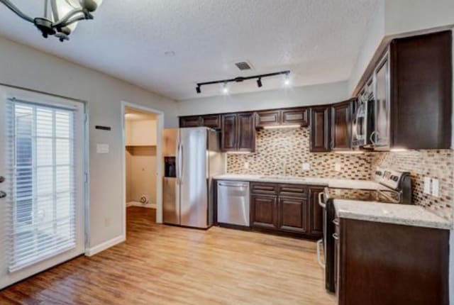 kitchen with light wood-type flooring, dark brown cabinets, and appliances with stainless steel finishes