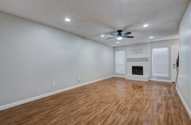 unfurnished living room with hardwood / wood-style floors, a textured ceiling, a fireplace, and ceiling fan