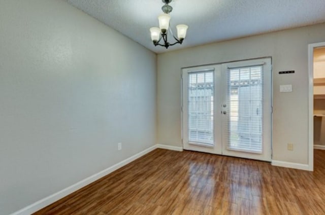 doorway to outside featuring french doors, a notable chandelier, a textured ceiling, and light wood-type flooring