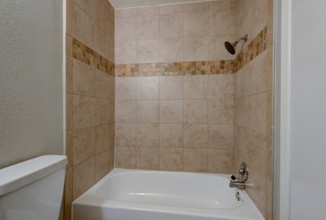 bathroom featuring tiled shower / bath and toilet