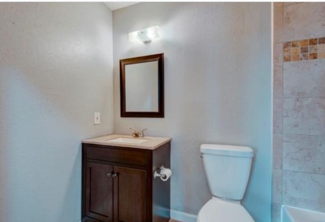 full bathroom featuring tiled shower / bath, vanity, and toilet