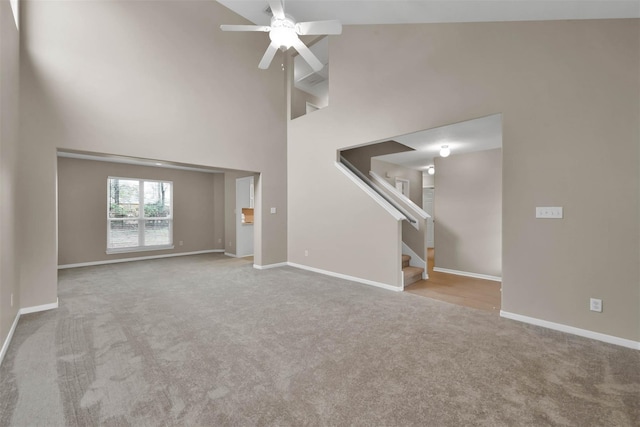 unfurnished living room featuring light colored carpet, ceiling fan, and a high ceiling