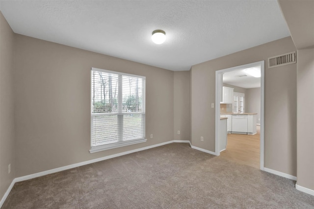 carpeted spare room with a textured ceiling