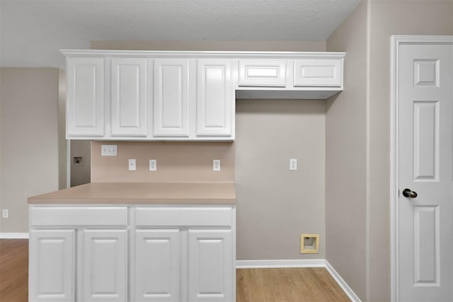 kitchen with white cabinetry, a textured ceiling, and light wood-type flooring