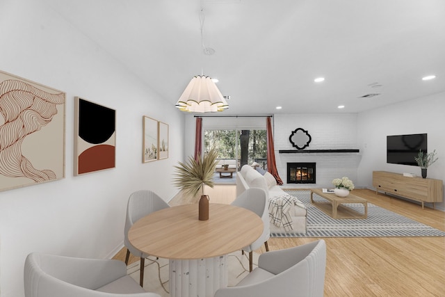 dining space featuring a brick fireplace and light hardwood / wood-style floors