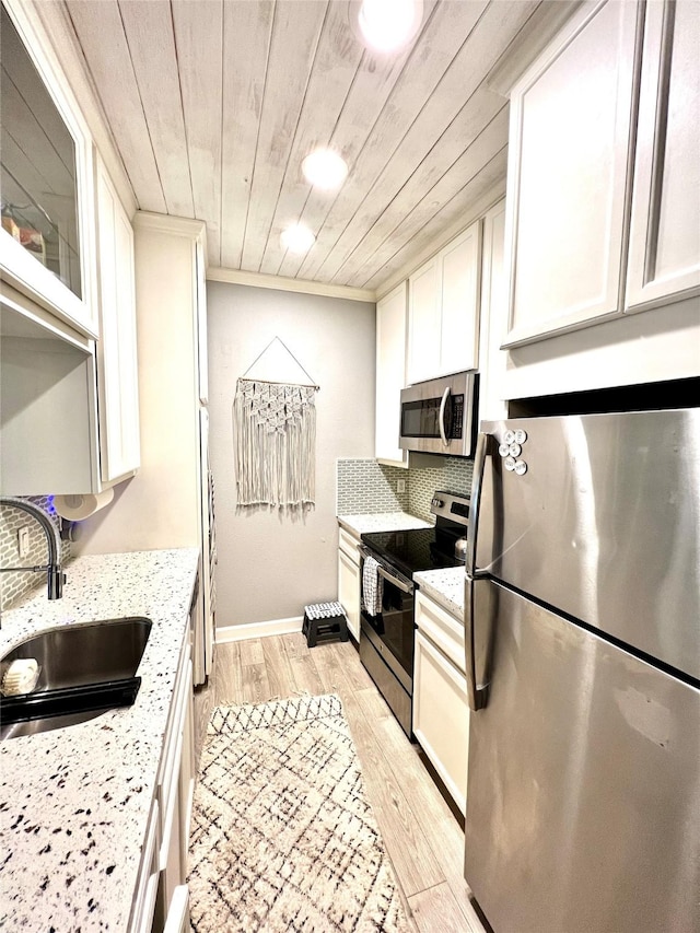 kitchen featuring sink, white cabinetry, light wood-type flooring, appliances with stainless steel finishes, and light stone countertops