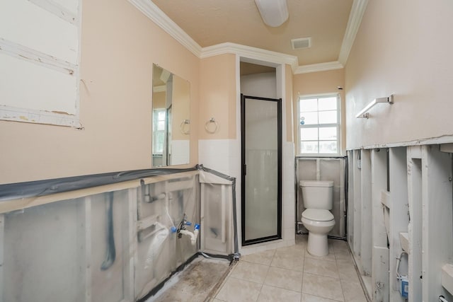 bathroom featuring tile patterned floors, toilet, a shower with shower door, tile walls, and ornamental molding