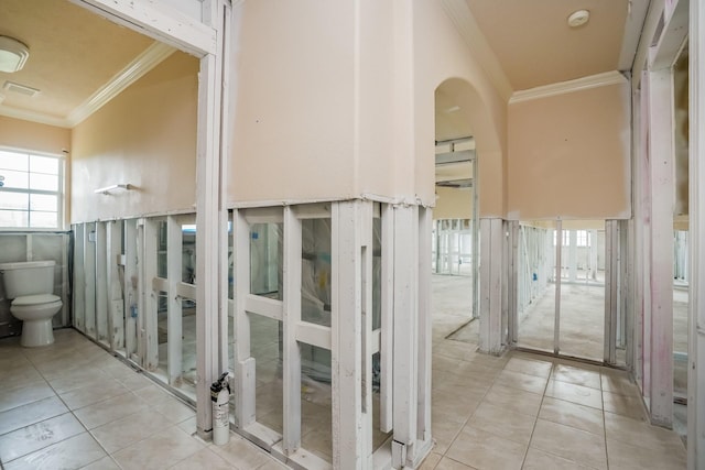 hallway featuring ornamental molding and light tile patterned floors