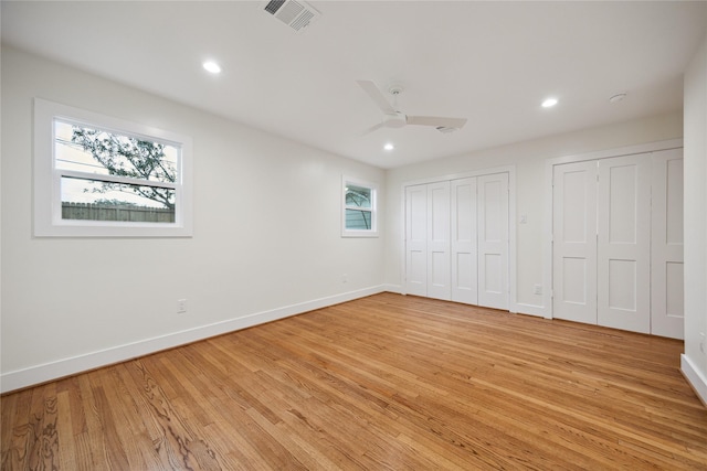 unfurnished bedroom featuring multiple closets, ceiling fan, and light hardwood / wood-style flooring