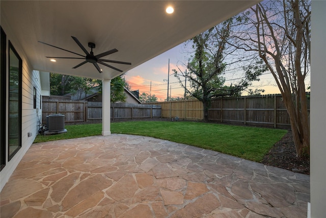 patio terrace at dusk with ceiling fan, a yard, and central air condition unit