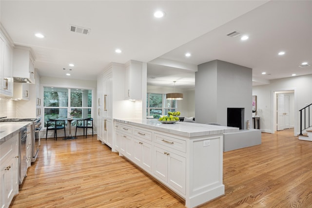 kitchen featuring white cabinetry, tasteful backsplash, light hardwood / wood-style floors, and appliances with stainless steel finishes