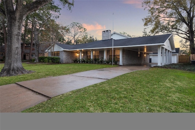 single story home featuring a carport and a lawn