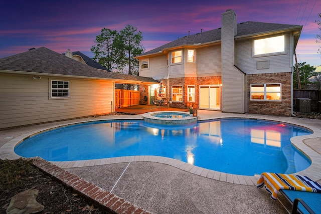 pool at dusk featuring an in ground hot tub and a patio area