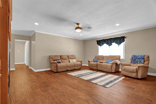 living room featuring ceiling fan, ornamental molding, wood-type flooring, and a textured ceiling